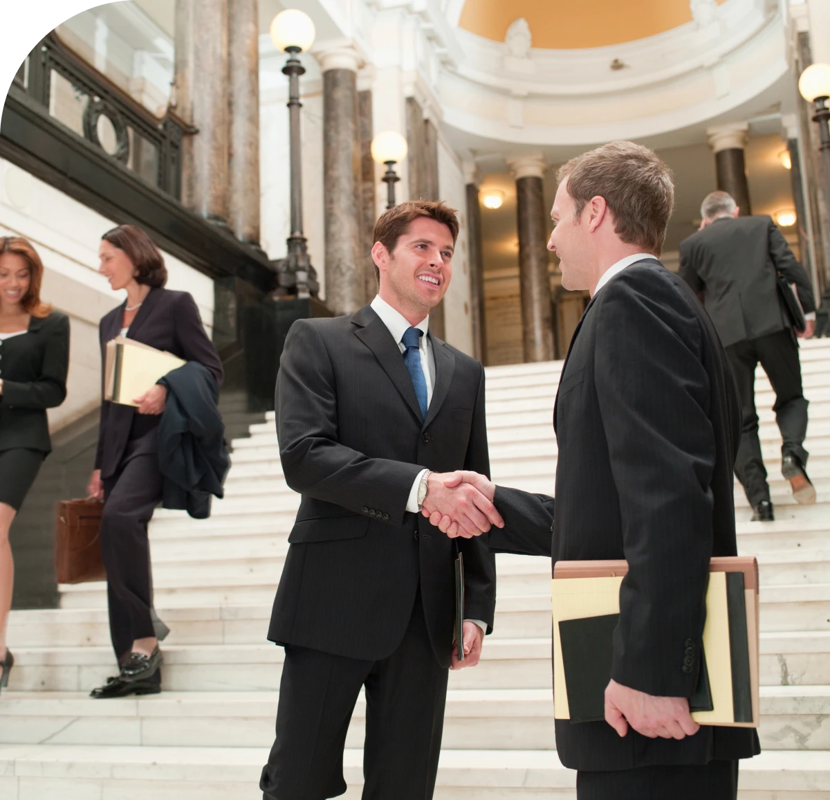 Businessmen shaking hands on grand staircase.